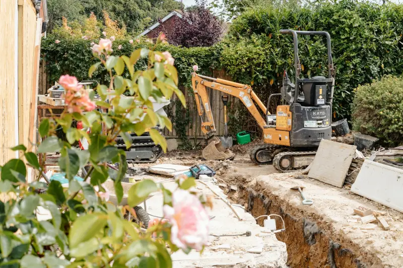 A mini excavator digging a trench in a residential yard